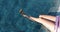 Close-up of the slender legs against the blue water in the resort pool under the sun, in the summer. Woman dangles her legs in the