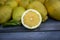 Close up of a Slice of lemon along with a group of lemons on a wood table