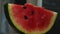 Close-up of a slice of red watermelon with seeds. The camera flies around. Parallax effect. In the background, a blurry map of the