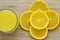 Close up of sliced orange and a full glass of orange juice on wooden surface