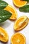 Close up of sliced oranges with green leaves on white background. Healthy refreshing citrus fruits. Top view