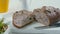 Close-up of sliced rye raisin bread on the white cutting board. There are also fresh veggies, white milk jug and yellow mug on the