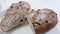 Close-up of sliced rye raisin bread on the white cutting board. There are also fresh veggies, white milk jug and yellow mug on the