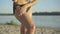 Close-up of slim tanned Caucasian female legs at sunset. Unrecognizable young woman spraying and rubbing sunscreen on