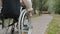 Close-up slow motion of disabled woman riding wheelchair outdoors in park