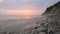 Close-up slow motion low wide angle small sea waves rolling on a rocky beach. Movement along the beach forward. Seaside