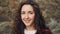 Close-up slow motion portrait of pretty girl brunette with curly hair looking at camera with serious face then smiling