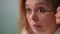 Close-up. Slow motion. A woman applies mascara to her eyelashes with a brush.