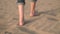 Close up, Slow motion. Woman feets walking on golden sand at the beach.