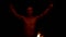 Close-up slow motion of a young man in black pants in total darkness shows a representation of a rotating burning torch