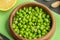 Close-up of a small amount of green peas in a wooden plate