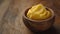 Close-up a small bowl of vibrant yellow ghee butter, placed on a wooden surface, with copy-space. Concept: natural, organic, and