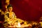 Close up of small buddha statue with glowing diya against blurry red golden background. buddhism and faith concept