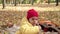 Close up small cheerful Preschool child in warm red hat eats licks large candy on stick. Kid eating sweets outside