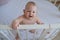 Close-up of a small child standing in a crib. The toddler does not want to sleep in the bed.