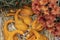 Close up of a small fresh orange pumpkin of different forms against the stray and autumn flowers background