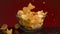 Close up of a small glass bowl and many potato chips falling into it and on the dark table. Stock footage. Spicy