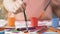 Close-up of small hand putting drawing brush in colorful palette, painting