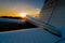 Close-up of a small parked plane with a propeller against the backdrop of a sunset.