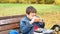 Close-up of a small schoolboy sitting on a Park bench and opening his school backpack during a lunch break. eating a