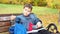 Close-up of a small schoolboy sitting on a Park bench and opening his school backpack during a lunch break. eating a