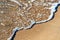 Close up of small sea waves with clear blue water over yellow sand beach at summer sunny shore