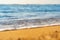 Close up of small sea waves with clear blue water over yellow sand beach at summer sunny shore