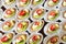 Close up of small sweet canapes arranged on a mirror plate over light background