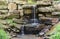 Close up of a small waterfall spilling over moss covered rocks in regional park. Handmade river waterfall