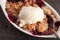 Close up of small white aramekian bowl of boysenberry cobbler