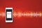 Close-up of smart phone and Audiobook on red background with Audio track. Audio, listen. Audiobook concept