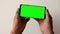 Close-up of a smartphone with a green screen in the hands of a pensioner.Mobile device in the hands of an elderly man. Smartphone