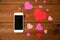 Close up of smartphone and hearts on wood