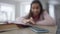 Close-up of smartphone ringing on table with blurred African American schoolgirl declining call studying at background