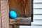 Close up of smiley face decorated egg hidden in the eaves of a shed for an Easter egg hunt in backyard.