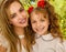 Close up of a smiling beautiful mom hugging her pretty daugher in beige dress wearing two red ties in hair