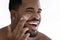 Close up of smiling biracial man use moisturizing face cream