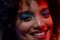 Close up of smiling biracial woman wearing blue eye shadow in red light