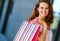 Close-up of smiling, brown-haired woman holding a stripey bag