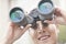 Close up of smiling businessman looking through binoculars, blue reflection in the glass