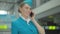 Close-up of smiling confident woman talking on the phone in airport terminal. Portrait of happy young stewardess telling