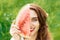 Close up of a smiling girl is holding watermelon slice covers half part of face