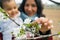 close up of smiling mother and baby daughter picking up cherry flowers during blossom season in spring. concept of motherhood and