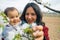 close up of smiling mother and baby daughter picking up cherry flowers during blossom season in spring. concept of motherhood and