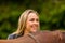 Close-up of smiling woman patting her arabian horse with grass in the field