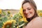 Close up of smiling young woman with eyes closed touching sunflower on face at field