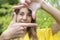 Close up of smiling young woman framing her face with her hands as a self-portrait