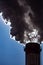 A close-up of the smoking chimneys of a coal-fired power plant.