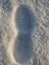 Close-up of a snowy male footprint in the snow. A large footprint left by a man in the snow