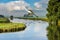 Close up of a soaring Great Egret above a farmers canal and background with green peat meadows